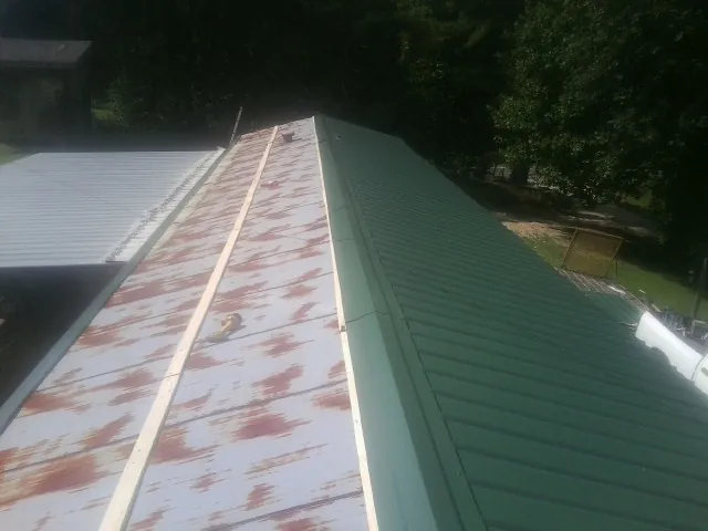 Old rusted panels beside newly installed green metal roofing — Wind Damage Roof Repair by Roofing Brothers in Seaside Heights