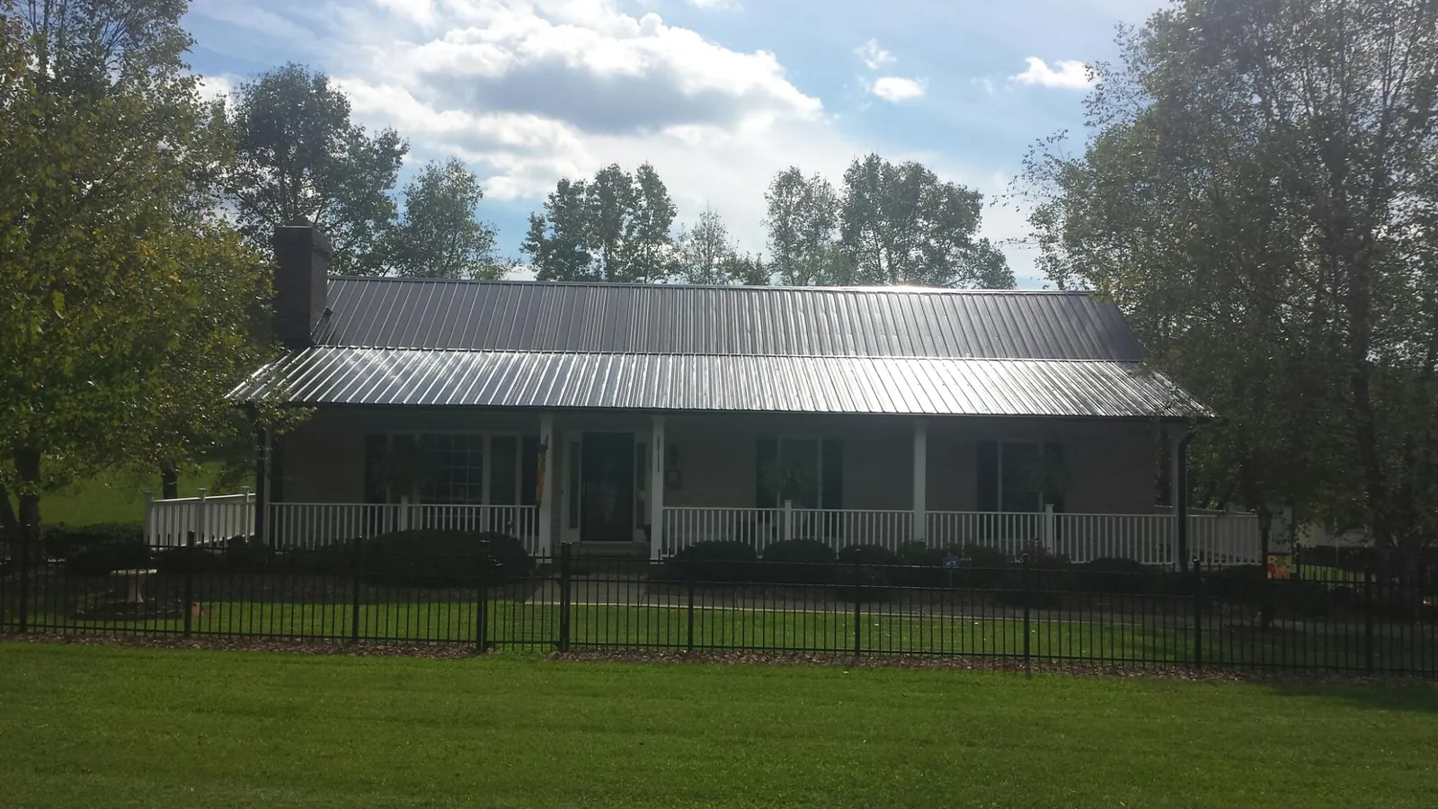 Gray metal roof on a brick ranch with a full width front porch — Gutter Guard Installation work by our crew in Seaside Heights