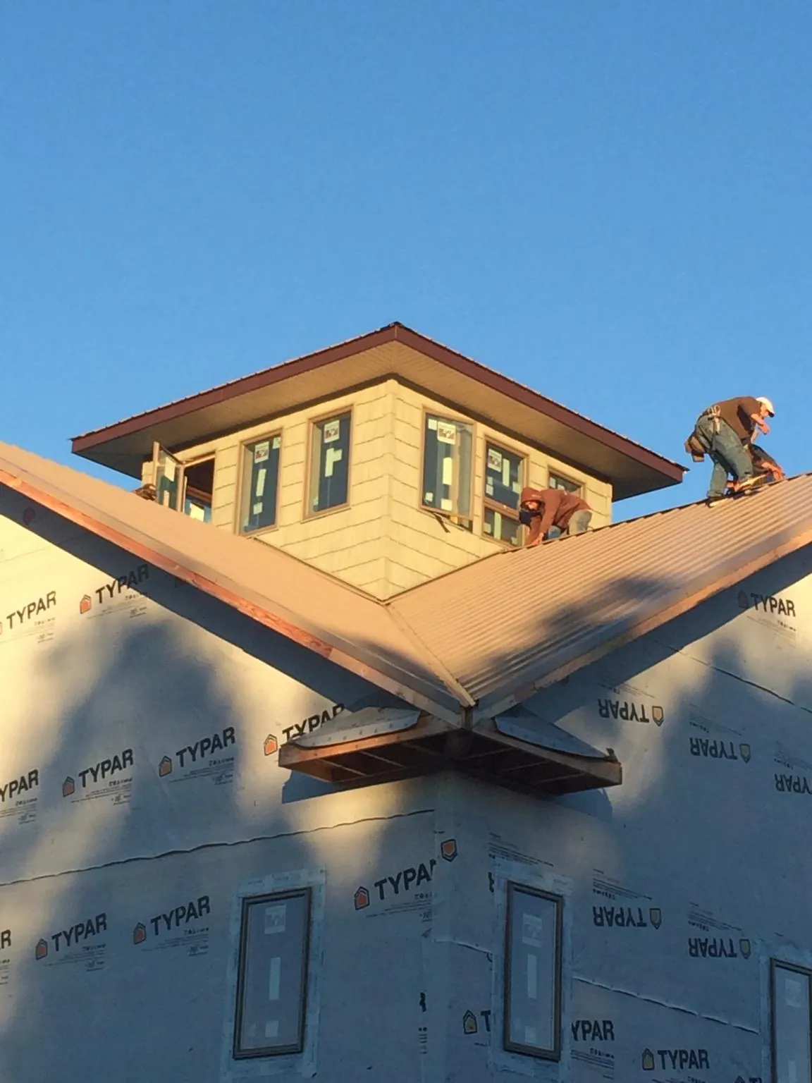 Roofers working around a rooftop cupola on a new metal roof at sunset — Roof Waterproofing in Seaside Heights by Roofing Brothers